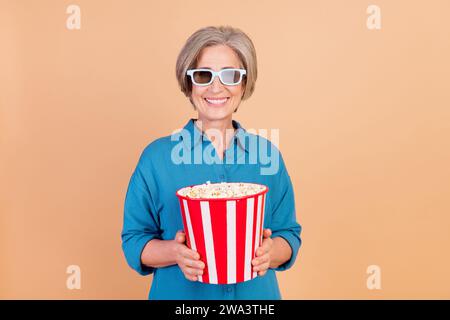 Photo de femme joyeuse avec bob hairdo habillé chemise bleue dans des verres 3d tiennent le pop-corn au cinéma isolé sur fond de couleur pastel Banque D'Images