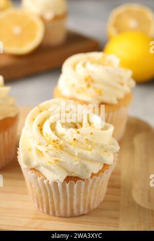 Délicieux cupcakes à la crème et zeste de citron sur planche de bois, gros plan Banque D'Images