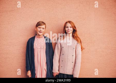 Portrait de deux jolies petites filles préadolescentes portant un pull tricoté et une veste, des amis jouant ensemble à l'extérieur. Mode pour adolescents. Kneatwear Banque D'Images
