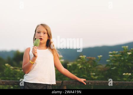 Adorable petite fille mangeant à la maison de la crème glacée fraîche à l'extérieur sur la chaude journée ensoleillée d'été Banque D'Images