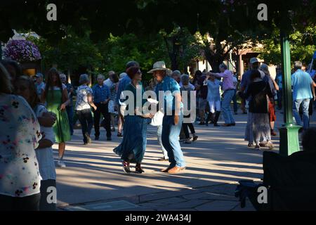 Les gens en chapeaux de cow-boy dansent sur la place de la ville. Banque D'Images