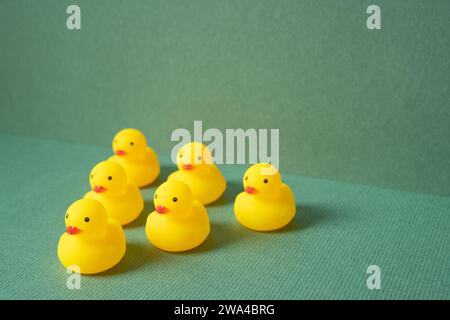 Rangée de poupée de canard en caoutchouc jaune sur fond vert. concept de leadership en équipe Banque D'Images