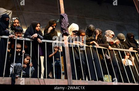 Femmes chiites regardant vers le bas la procession religieuse autour de la mosquée iranienne ( Mughal Masjid ) pendant le mois sacré de Mouharram. Mumbai, Inde. Banque D'Images