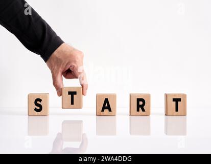 Pour faire un nouveau départ dans la vie, les affaires, l'éducation ou le concept de carrière. Main masculine arrange le mot start sur des cubes en bois. Banque D'Images