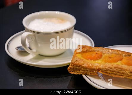 Pâtisserie traditionnelle française ou tarte aux abricots et une tasse de latte, café au lait dans une boulangerie artisanale à Strasbourg, Alsace, France Banque D'Images