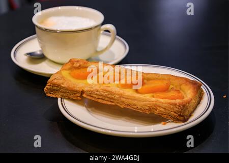 Pâtisserie traditionnelle française ou tarte aux abricots et une tasse de latte, café au lait dans une boulangerie artisanale à Strasbourg, Alsace, France Banque D'Images