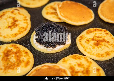 Blinis au caviar noir et fromage à la crème, sur un plat festif, mini crêpes, un élégant apéritif Banque D'Images