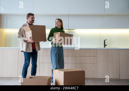 Heureux homme et femme de la famille porte des boîtes à la cuisine, déménage dans un nouvel appartement acheté avec hypothèque Banque D'Images