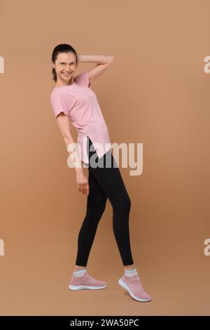 Une femme sportive se penche en arrière dans un studio, regardant la caméra portant des vêtements de fitness Banque D'Images