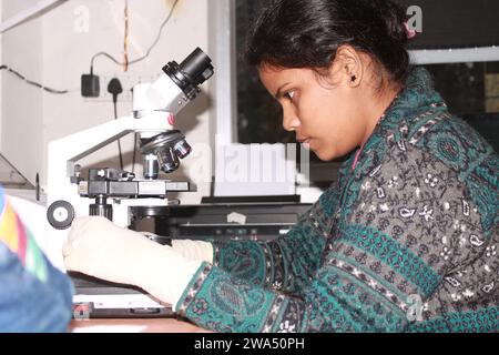 Lady pathologiste examinant au microscope. Inde Banque D'Images