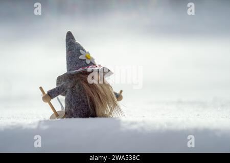 Elfe de Noël sur des skis et avec des bâtons de ski sur la neige blanche au soleil Banque D'Images