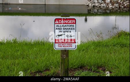 Un signe d'avertissement des alligators et des serpents dans la zone par un ruisseau en Floride USA. Banque D'Images