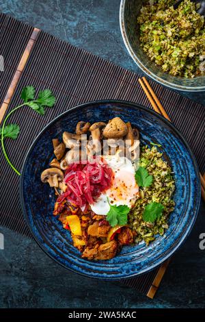 Bol diététique cétogène avec chou-fleur biologique et riz brocoli, poulet sauté, champignons, œuf et oignons. Nourriture saine sans gluten. Banque D'Images