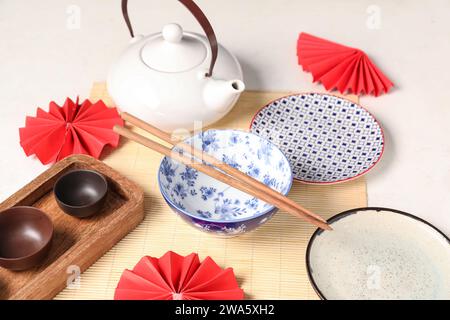 Théière avec vaisselle, baguettes et décor sur fond blanc. Réglage de table chinois Banque D'Images