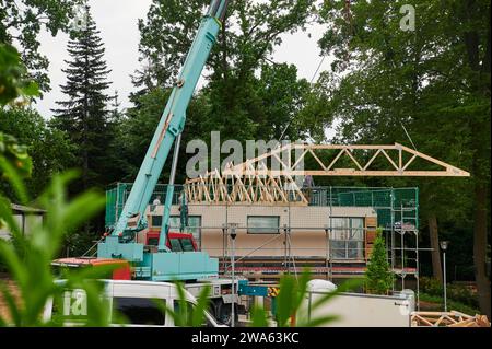 Bauhandwerk, Hausbau, Kran hebt Holzständerteile auf Rohbau für die Dachkonstruktion Arbeitsmittel *** Bâtiment, construction de maisons, grue soulève des pièces de charpente en bois sur la coque pour les équipements de construction de toits Banque D'Images
