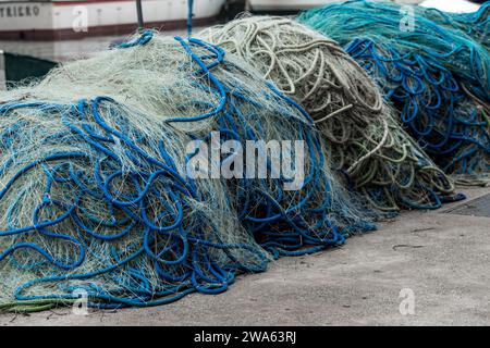 Une série de filets de pêche empilés sur le port près des bateaux de pêche après un voyage de pêche. Filets reliés par des cordes en plastique et des flotteurs de différentes couleurs. Banque D'Images