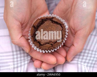 Une femme tenant un brownie au chocolat sans gluten dans ses mains. Gros plan. Banque D'Images
