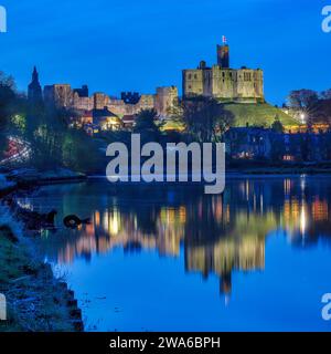 Vue au crépuscule du château de Warkworth et du village de Warkworth reflété dans la rivière Coquet comme vu de Amble avec le château de Warkworth inondé. Banque D'Images