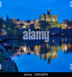 Vue au crépuscule du château de Warkworth et du village de Warkworth reflété dans la rivière Coquet comme vu de Amble avec le château de Warkworth inondé. Banque D'Images