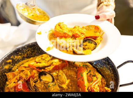 Gros plan d'une assiette de riz avec homard et fruits de mer servi par une femme Banque D'Images