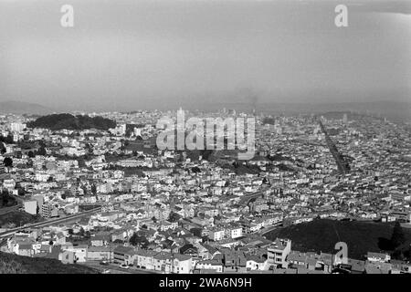 Blick auf San Francisco von den Twin Peaks aus, erkennbar zwischen den Gebäuden ist die breite Market Street und als bewaldeter Hügel der Buena Vista Park, 1962. Vue de San Francisco depuis les Twin Peaks, reconnaissable entre les bâtiments est la large Market Street et la colline boisée de Buena Vista Park, 1962. Banque D'Images