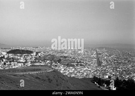 Blick auf San Francisco von den Twin Peaks aus, erkennbar zwischen den Gebäuden ist die breite Market Street und als bewaldeter Hügel der Buena Vista Park, 1962. Vue de San Francisco depuis les Twin Peaks, reconnaissable entre les bâtiments est la large Market Street et la colline boisée de Buena Vista Park, 1962. Banque D'Images