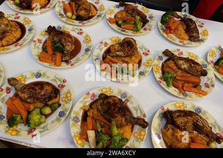 Assiettes de dîner de Noël alignées et prêtes à être servies dans une cuisine communautaire à Kilburn, Londres, avec poulet rôti et légumes. Banque D'Images