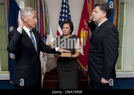 Forces militaires AMÉRICAINES. Lilibet Hagel, au centre, tient la Bible pour son mari Chuck Hagel, à gauche, alors qu'il est assermenté en tant que 24e secrétaire de la Défense par le directeur de l'administration et de la gestion du DoD Michael L. Rhodes, à droite, au Pentagone le 27 février 2013. Photo du DoD par le quartier-maître de 1e classe Chad J. McNeeley, U.S. Navy. (Publié) Banque D'Images