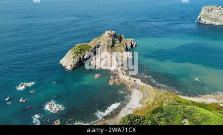 Vidéo aérienne par drone de Gaztelugatxeko San Joan baseliza, ermitage côtière à Biscaye en Espagne, avec un pont de pierre sinueux, un îlot rocheux et une vue sur le golfe de Gascogne Banque D'Images