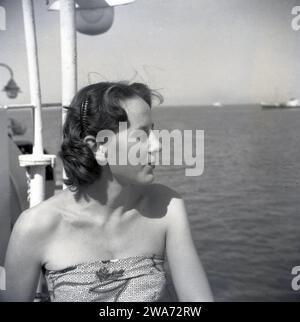 1953, historique, jeune femme en vacances sur l'île de Ceylan (Sri Lanka), assise sur un bateau regardant la mer. Située dans l'océan Indien en Asie du Sud, l'île est devenue une République socialiste démocratique en 1972 et a changé son nom pour Sri Lanka. Banque D'Images