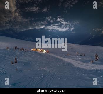 Tondeuses à neige (machines à ratraquer) en excursion nocturne avant l'aube jusqu'au sommet de la montagne en hiver avec des snowboarders freeriders. Station de ski alpin Dragob Banque D'Images