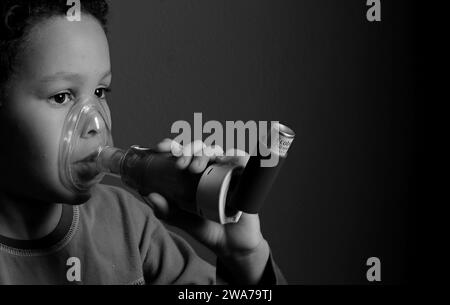 enfant avec la grippe avec inhalateur bouffée respiratoire sur fond gris avec des gens photo stock Banque D'Images