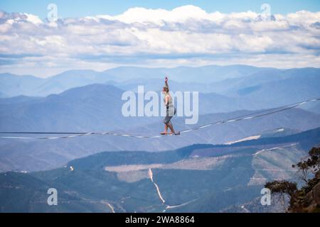 Slacklining à travers les Alpes australiennes. Un slackliner en équilibre haut à Mount Buffalo dans le Victoria, en Australie. Banque D'Images