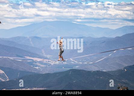 Slacklining à travers les Alpes australiennes. Un slackliner en équilibre haut à Mount Buffalo dans le Victoria, en Australie. Banque D'Images