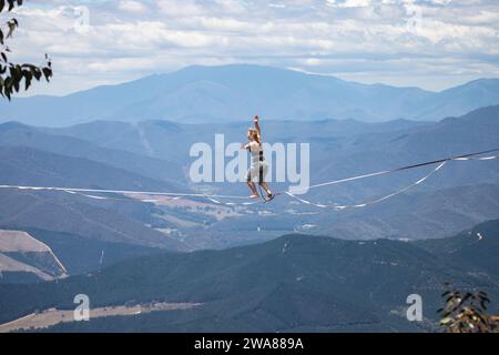 Slacklining à travers les Alpes australiennes. Un slackliner en équilibre haut à Mount Buffalo dans le Victoria, en Australie. Banque D'Images