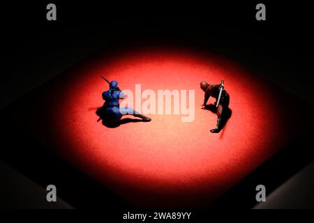 Photographie de figurine miniature créative de personnes. Installation de notes autocollantes. Deux ninja combattant sur l'arène rouge mat. Image photo Banque D'Images