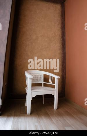 chaise en bois blanc dans le coin d'une pièce avec un plancher en bois Banque D'Images