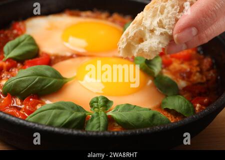 Femme mangeant délicieux Shakshuka avec du pain, gros plan Banque D'Images