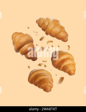 Délicieux croissants frais tombant sur fond beige Banque D'Images