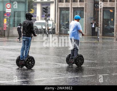 Touristes voyageant en Segway transporteurs personnels de l'autre côté d'une rue sous une pluie battante, Berlin, 23 06 2023 Banque D'Images