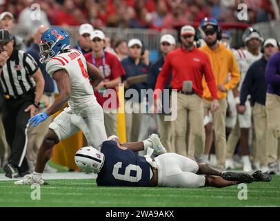 Mississippi Rebels Running Back Quinshon Judkins (4) monte sur le terrain tandis que la sécurité des Nittany Lions de Penn State Zakee Wheatley (6) s'accroche à sa jambe pendant le troisième quart-temps Chick-fil-A Peach Bowl College match de football entre Pen State vs Mississippi Rebels au stade Mercedes-Benz le 1er janvier 2023 à Atlanta, Géorgie. Les rebelles du Mississippi battent Pen State 38-25 (David Venezia / image du sport) Banque D'Images