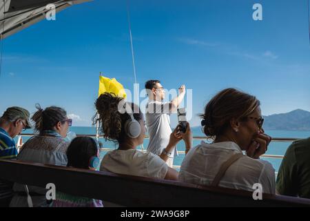 Koh Chang, Thaïlande. 28 décembre 2023. Les passagers sont vus prendre des photos du paysage, depuis le ferry sur le chemin de l'île de Koh Chang. Le ferry pour l'île de Koh Chang part du continent Ao Thammachat Pier sur le continent pour arriver à Ao Sapparot Pier sur la côte nord-est de Koh Chang. L'île de Koh Chang, connue sous le nom d'« île des éléphants » en raison de son promontoire en forme d'éléphant, est la troisième plus grande île de Thaïlande après Phuket et Samui. Crédit : SOPA Images Limited/Alamy Live News Banque D'Images