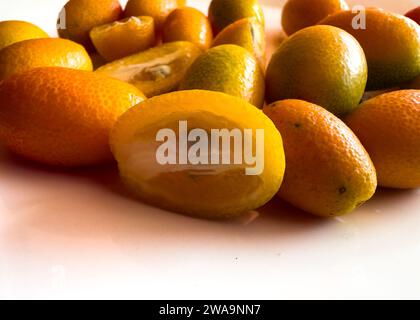 Gros plan d'un fruit kumquat demi tranché isolé sur fond blanc Banque D'Images