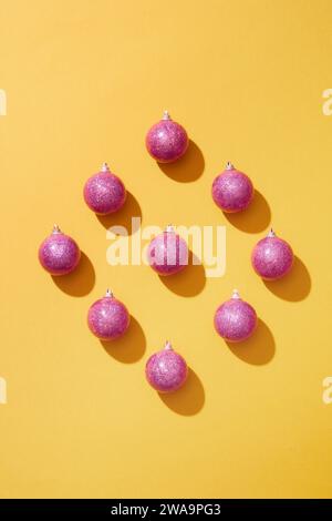 Vue de dessus de quelques boules roses sur surface jaune. Pour le concept de noël. Noël n'a jamais manqué d'attirer les gens avec diverses façons de célébrer Banque D'Images