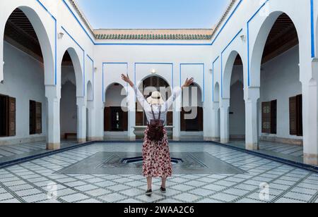 Jeune femme avec robe rouge et chapeau visitant l'architecture marocaine typique à Marrakech. Maroc - concept de style de vie de voyage et de vacances Banque D'Images