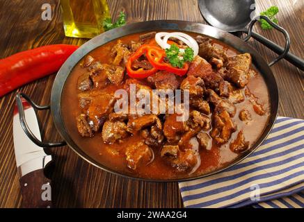 Viande fine - Goulash de bœuf dans une casserole avec du poivre rouge sur fond en bois Banque D'Images