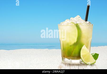 Caipirinha cocktail sur un fond de plage avec vue sur l'océan et ciel bleu Banque D'Images
