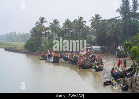 Vue de paysage de bateaux traditionnels en bois connus sous le nom de moon boats sur la rive de la rivière sous la pluie, Cox's Bazar, Bangladesh Banque D'Images