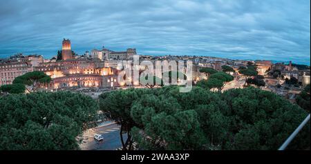 Vue du soir sur le célèbre colisée de rome, vu de loin. Route visible et arbres menant au célèbre amphithéâtre, d'autres maisons et ruines visibles arou Banque D'Images