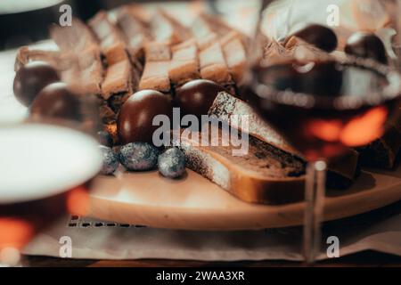 Nourriture typique de pâques - oeufs durs, radis de cheval, potica, bonbons et jambon. Tous ensemble sur une table, joliment servi avec un verre de vin rouge. Banque D'Images